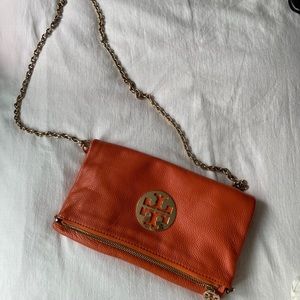 Orange clutch from Tory Burch. With golden shoulder chain.